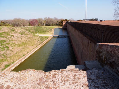 [Wooden drawbridge leading from between small hills to fort wall.]